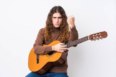 Gitar çalan beyaz bir adam kameraya yumruk atıyor, agresif bir yüz ifadesi var..