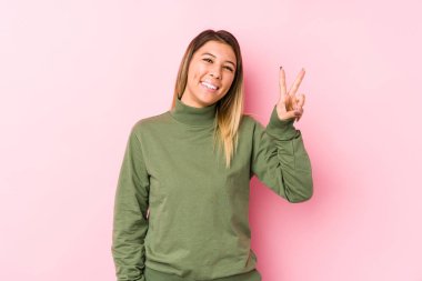 Kafkasyalı genç kadın izole bir şekilde poz veriyor zafer işareti gösteriyor ve gülümsüyor..