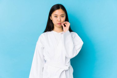 Genç Çinli kadın karate yapıyor. Parmakları dudaklarında ve sır saklıyor..