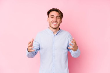 Pembe arka planda poz veren beyaz bir genç neşeli bir şekilde gülüyor. Mutluluk kavramı.
