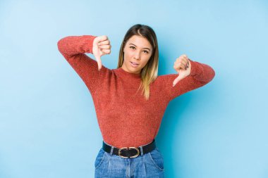 Kafkasyalı genç bir kadın soyutlanmış poz veriyor başparmağını aşağı gösteriyor ve hoşlanmadığını ifade ediyor..