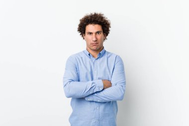 Genç, kıvırcık, olgun, zarif bir gömlek giyen mutsuz, iğneleyici bir ifadeyle kameraya bakan bir adam..