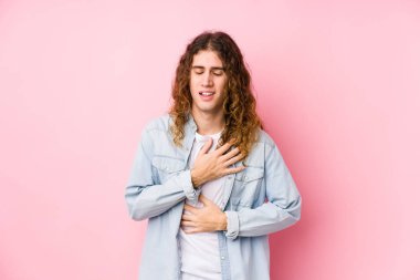 Uzun saçlı adam mutlu mesut gülüyor ve ellerini karnının üstünde tutarak eğleniyor..