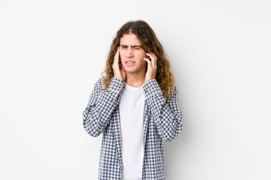 Genç, uzun saçlı adam elleriyle kulaklarını kapatmış poz veriyor..