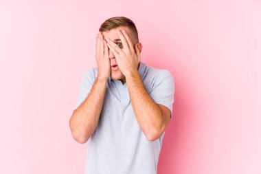 Kafkasyalı genç bir adam parmaklarının arasından ürkmüş ve gergin bir şekilde göz kırpıyor..