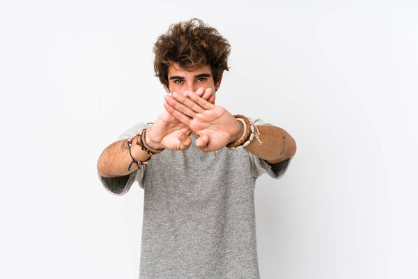 Young caucasian man against a white background isolated doing a denial gesture