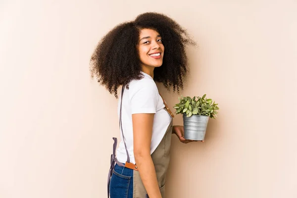 Młoda Afro Ogrodnik Kobieta Trzyma Roślinęizolowane Spojrzenia Bok Uśmiechnięty Wesoły — Zdjęcie stockowe