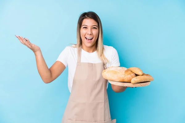 Young caucasian baker woman isolated receiving a pleasant surprise, excited and raising hands.
