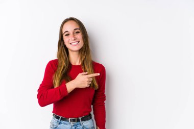 Yalnız poz veren beyaz bir kadın gülümsüyor ve boş alanda bir şeyler gösteriyor..