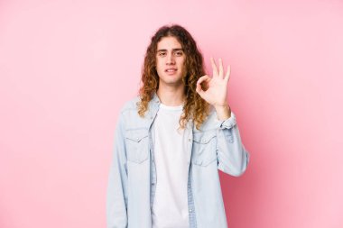 Uzun saçlı adam neşeli ve kendinden emin bir şekilde poz veriyor..