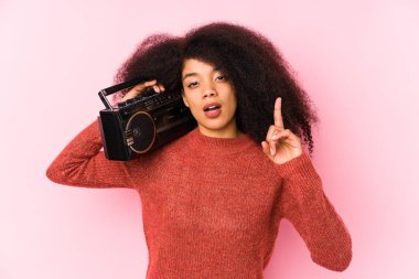 Young afro woman holding a cassete isolated having an idea, inspiration concept.