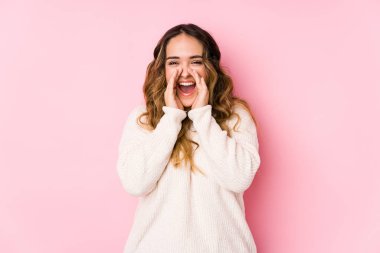 Pembe arka planda poz veren kıvrımlı genç bir kadın..