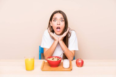 Genç, beyaz bir kadın kahvaltı yapıyor. Şaşırmış ve şok olmuş..