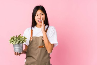 Genç Çinli bahçıvan bir bitkiyi tek başına tutuyor. Gizli bir sıcak fren haberi veriyor ve yana bakıyor.