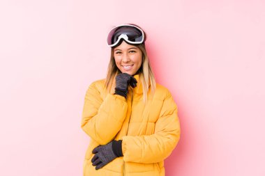 Young caucasian woman wearing a ski clothes in a pink background smiling happy and confident, touching chin with hand.