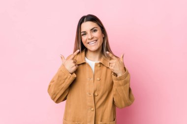 Kafkasyalı genç bir kadın tebessüm ediyor, parmaklarını ağzına doğrultuyor..