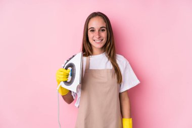 Young caucasian woman with clothes iron isolated happy, smiling and cheerful.