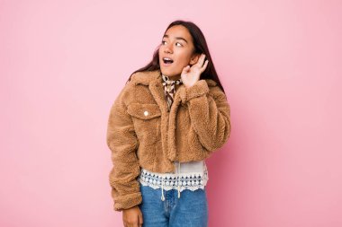 Bir dedikoduyu dinlemeye çalışan kısa bir koyun derisi ceket giyen genç Hintli kadın..