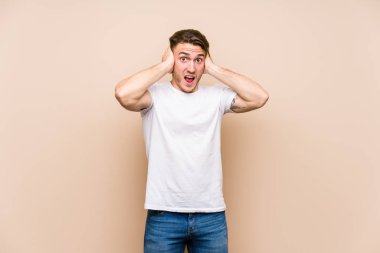 Kafkasyalı genç adam, yalıtılmış poz veriyor. Kulaklarını elleriyle kapatıyor. Gürültülü sesler duymamaya çalışıyor..