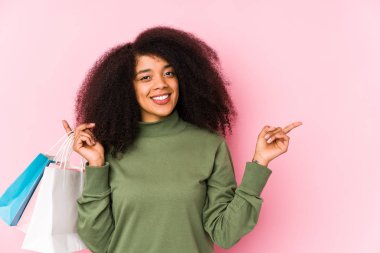 Genç afro kadın alışverişte soyutlanmış afro kadın yalnız başına bir afro kadın satın alıyor. Güller tutuyor, gülümsüyor ve boş alanda bir şeyler gösteriyor..