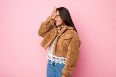 Kısa bir koyun derisi ceket giyen genç Hintli kadın bir şeyi unutuyor, alnına avuç içi ve kapalı gözlerle vuruyor..