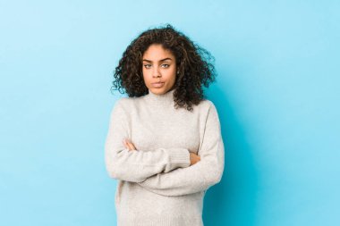 Afro-Amerikan kıvırcık saçlı, hoşnutsuzca kaşlarını çatan, kollarını kavuşturan genç bir kadın..