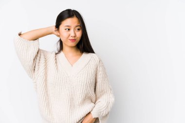 Young chinese woman isolated touching back of head, thinking and making a choice.