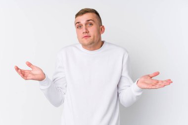 Beyaz arka planda genç beyaz bir adam sorgulama sırasında omuz silkiyor ve şüphe ediyor..