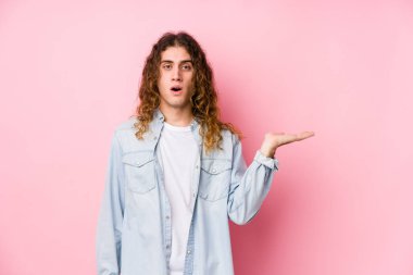 Uzun saçlı adam yalnız poz veriyor. Kopya alanını avucunun içinde tutmaktan etkilenmiş..