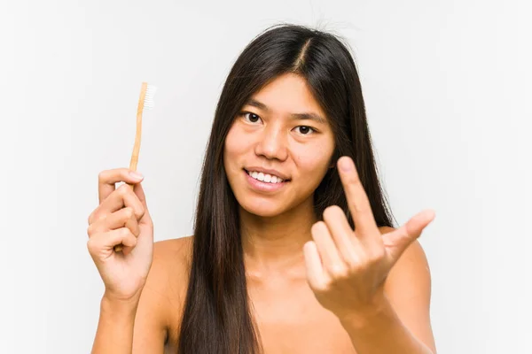 年轻的中国女人拿着牙刷 用手指指著你 好像在邀请你走近些 — 图库照片