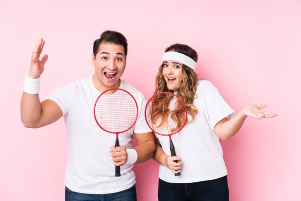 Casal Jovem Jogando Badminton Isolado Recebendo Uma Agradável Surpresa Animado — Fotografia de Stock