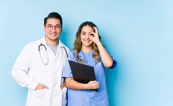 Young Doctor Couple Posing Blue Background Isolated Excited Keeping Gesture — 스톡 사진