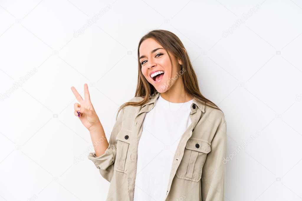 Young caucasian woman  isolated joyful and carefree showing a peace symbol with fingers.