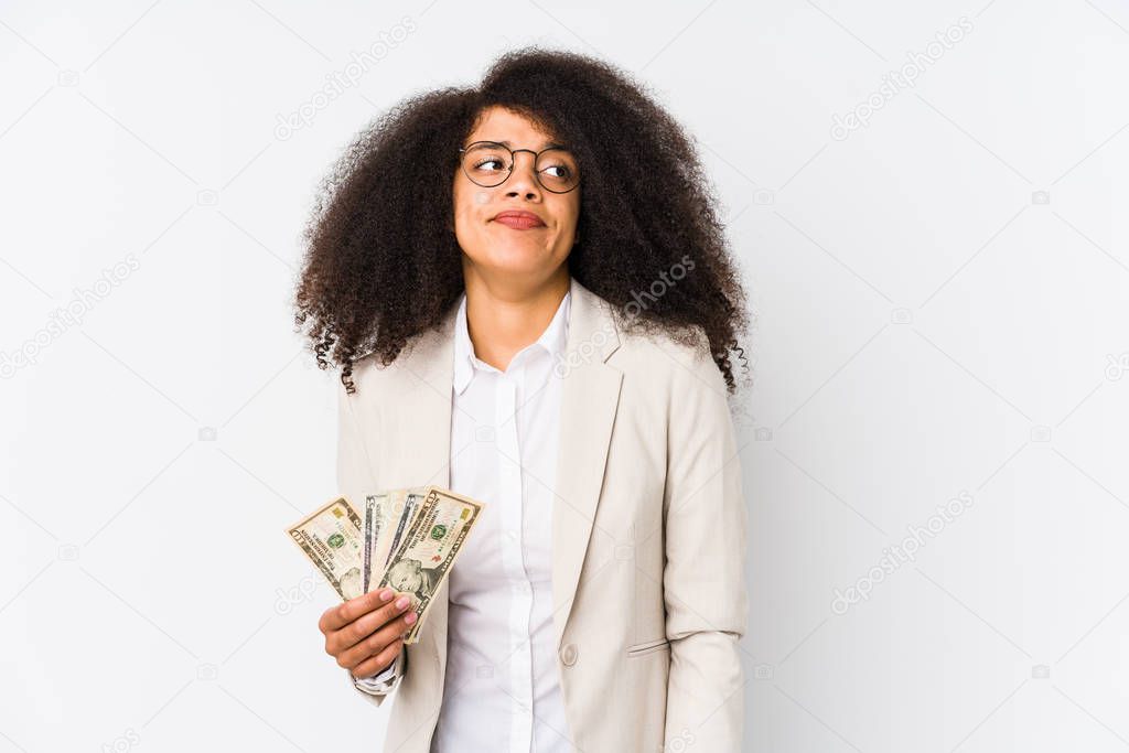 Young afro business woman holding a credit car isolated Young afro business woman holding a credit carconfused, feels doubtful and unsure.