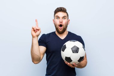 Elinde futbol topu tutan genç beyaz bir adamın harika bir fikri var, yaratıcılık kavramı..