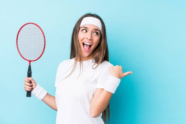 Badminton oynayan beyaz bir kadın parmak kadar uzakta, gülerek ve kaygısız bir şekilde izole edilmiş noktalar..