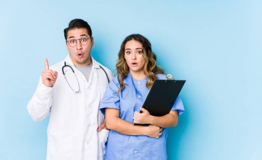 Mavi arka planda poz veren genç doktor çiftin harika bir fikri var, yaratıcılık kavramı..