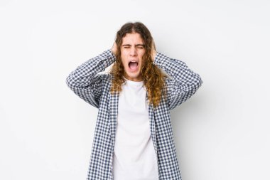 Uzun saçlı genç adam, yalıtılmış poz veriyor. Kulakları elleriyle kapatıyor. Gürültülü sesler duymamaya çalışıyor..