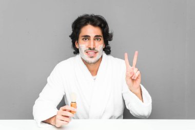 Sakalını kesen genç adam zafer işareti gösteriyor ve gülümsüyor..