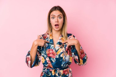 Pijama giyen genç beyaz kadın parmaklarıyla işaret ederek, geniş bir gülümsemeyle şaşırdı..