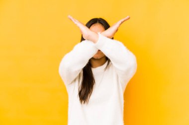 Sarı arka planda izole edilmiş genç bir kadın iki kolu çapraz tutuyor, inkar kavramı.