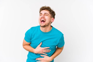 Sarışın, kıvırcık saçlı, beyaz tenli bir adam mutlu mesut gülüyor ve ellerini karnının üstünde tutarak eğleniyor..