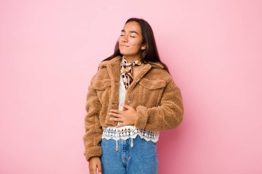 Koyun derisi ceket giyen genç bir Hintli kadın göbeğine dokunuyor, nazikçe gülümsüyor, yemek yiyor ve tatmin oluyor..