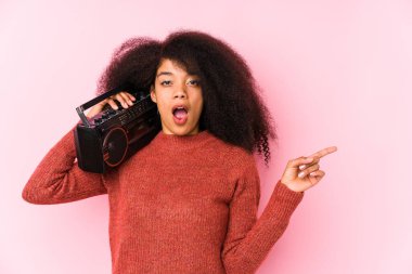 Elinde kaset tutan genç bir afro kadın yan tarafı gösteriyor.