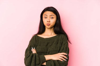 Pembe arka planda izole edilmiş genç Çinli kadının yanakları şişer, yorgun bir ifadesi vardır. Yüz ifadesi kavramı.