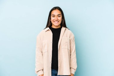 Mavi bir arka planda izole edilmiş genç bir kadın mutlu, güler yüzlü ve neşeli..