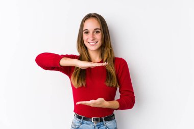 Kafkasyalı genç bir kadın iki eliyle bir şey tutuyormuş gibi poz veriyor, ürün sunumu..