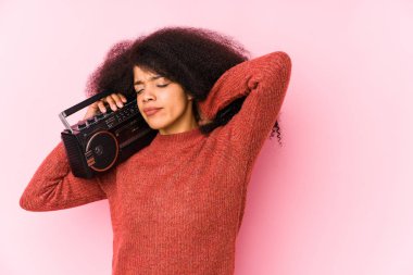 Elinde kaset tutan genç bir afro kadın kafasının arkasına dokunuyor, düşünüyor ve bir seçim yapıyor..