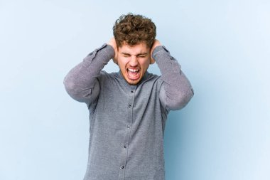 Sarışın, kıvırcık saçlı, beyaz tenli bir adam. Kulaklarını kapatmış, yüksek sesli sesler duymamaya çalışıyor..