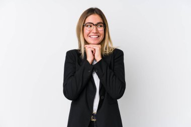 Genç beyaz kadın ellerini çenesinin altında tutuyor, mutlu bir şekilde yan tarafa bakıyor..